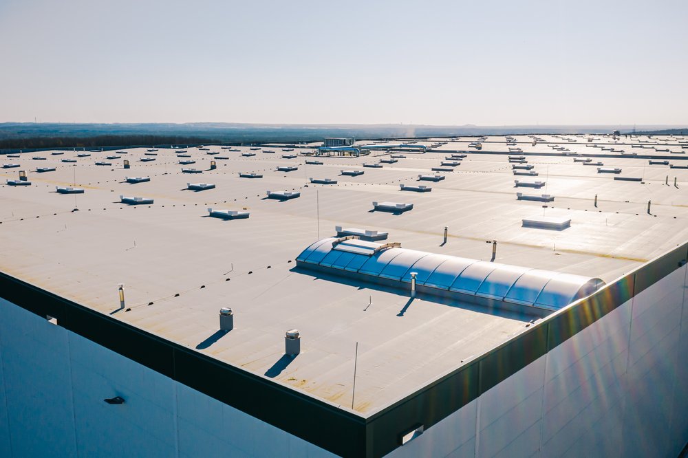 Commercial flat roof with vents and skylights under clear sky